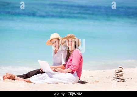 Happy couple using laptop on the beach, Maldives Stock Photo