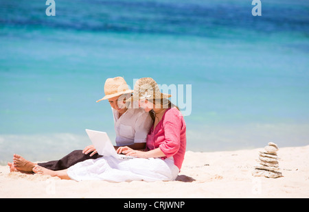 Happy couple using laptop on the beach, Maldives Stock Photo