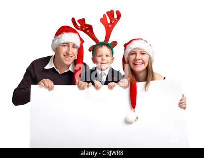 smiling young family wearing Santa caps of an elk antler holding an empty white panel Stock Photo