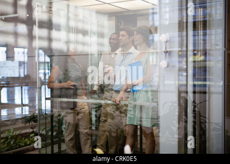 Business people riding glass elevator Stock Photo