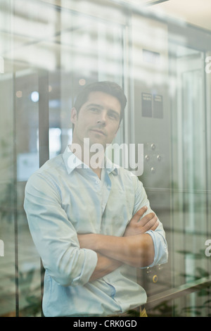 Businessman riding glass elevator Stock Photo