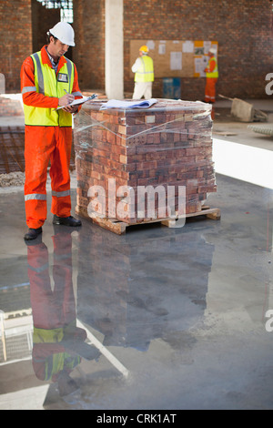 Worker writing on clipboard on site Stock Photo