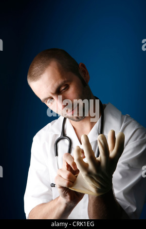 A young male nurse putting on protective surgical gloves. Stock Photo