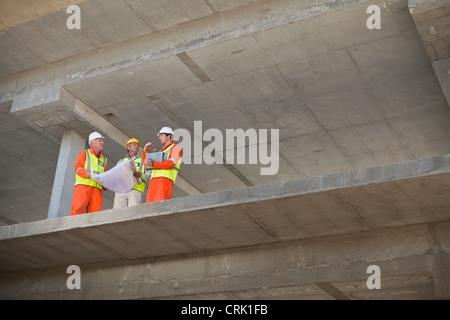 Workers reading blueprints on site Stock Photo
