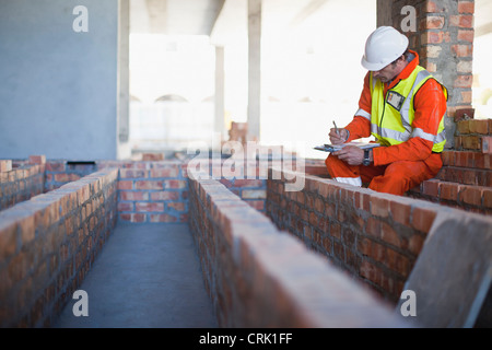 Worker writing on clipboard on site Stock Photo