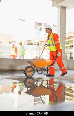 Worker carting concrete on site Stock Photo