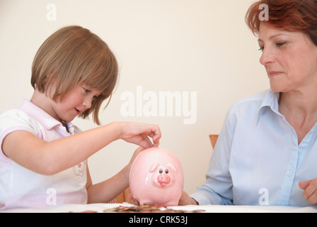 Daughter putting money in piggy bank Stock Photo