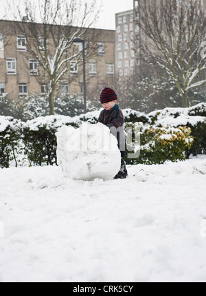 Boy building snowman in park