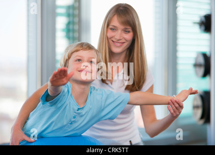 Trainer working with boy in gym Stock Photo