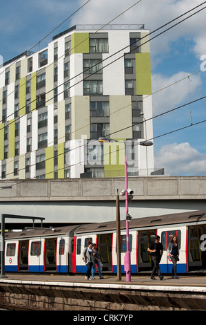 Passengers walking along a platform alongside a London Underground train at a railway station, England. Stock Photo