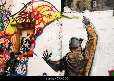 Graffiti of graffiti artist spray painting a wall in an alley in downtown Aberdeen, Washington. Stock Photo