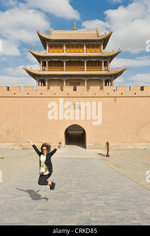 A Chinese tourist jumping for joy at the Jiayuguan Pass Tower and Huiji door on the western side of the Guan City of Jiayuguan. Stock Photo
