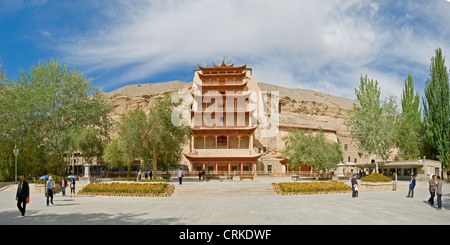 A 2 picture stitch panoramic of tourists outside Cave 96 - probably the most well known of the Mogao Caves. Stock Photo