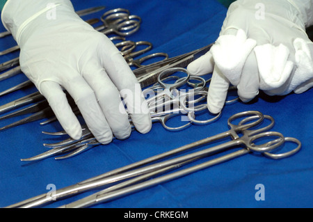 The hands of a surgeon's assistant arranges various surgical instruments. Stock Photo