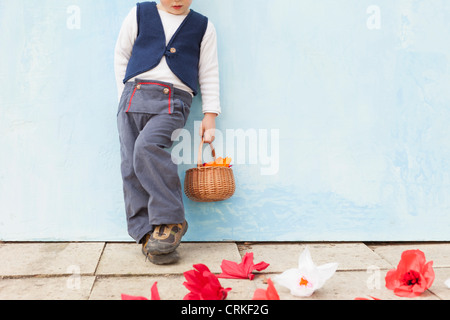 Boy holding basket of paper flowers Stock Photo