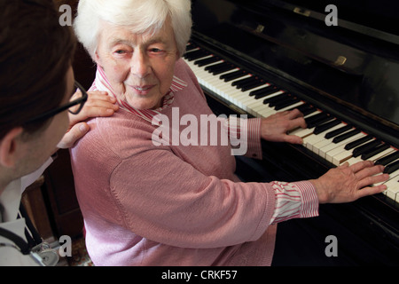 Doctor watching older woman play piano Stock Photo