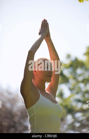 A young woman practicing yoga outside, standing in tree pose Stock Photo