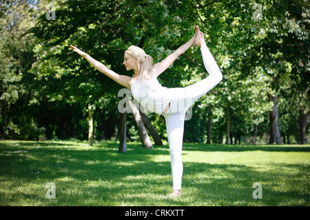 A young woman practicing yoga outside, king dancer pose Stock Photo