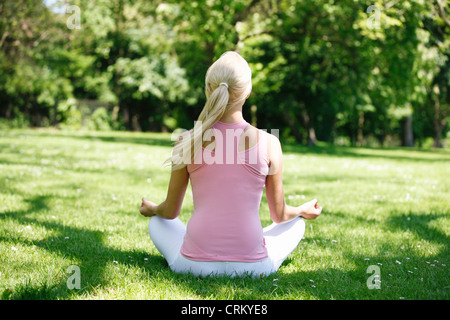 A young woman meditating outside, view form behind Stock Photo