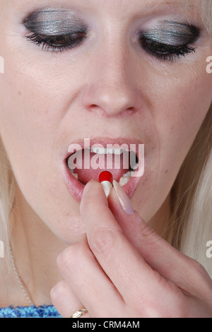 Woman holding a painkiller between finger Stock Photo