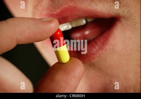 Close-up a man taking a red and yellow capsule. Stock Photo