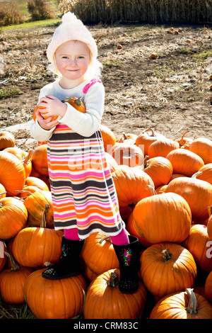 Portrait of a young girl standing on pumpkin Stock Photo