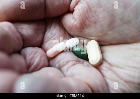An assortment of medication tablets in the hand of an elderly man. Stock Photo