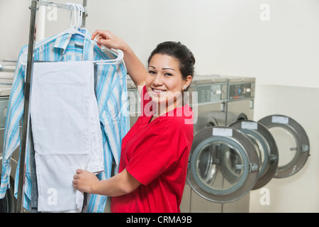 Portrait of a happy young woman drying clothes in Laundromat Stock Photo