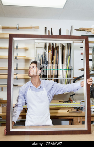 Young craftsman looking on frame's corner in workshop Stock Photo