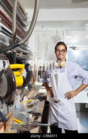 Portrait of a skilled worker standing with hands on hips in workshop Stock Photo