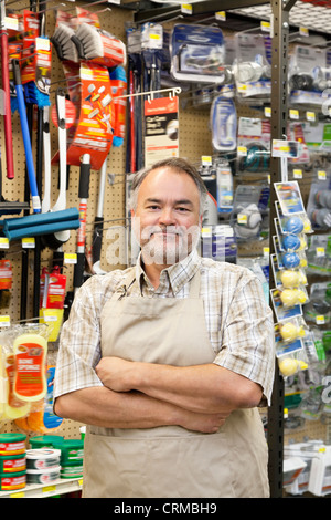 Portrait of a confident mature store clerk with arms crossed in hardware shop Stock Photo
