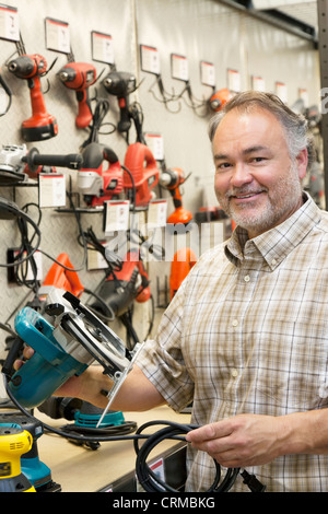 Portrait of a happy hardware store owner with electric saw Stock Photo