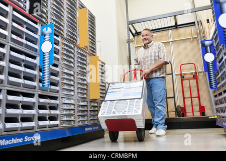 Mature man pushing handtruck in hardware store Stock Photo