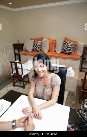 Happy mid adult woman getting nails polished Stock Photo