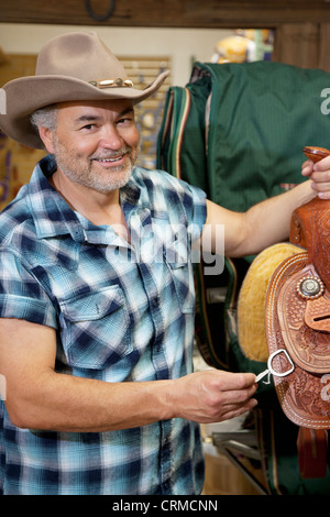 Portrait of a happy cowboy with riding tack in feed store Stock Photo