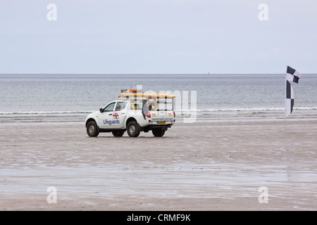Lifeguard patrol on the beach at Westward Ho !, England next to a flag indicating a safe surfing area Stock Photo