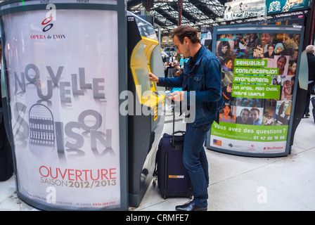 Paris, France, Tourists Traveling in Train Station, Gare de Lyon, Man using Ticket Vending Machine with Advertising French Poster, commercial ad, billboard, SNCF, outdoor advertising poster,  sncf ticket Stock Photo