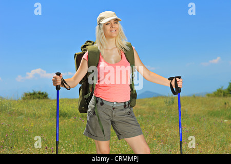 A smiling woman posing with backpack and hiking poles posing outdoor Stock Photo