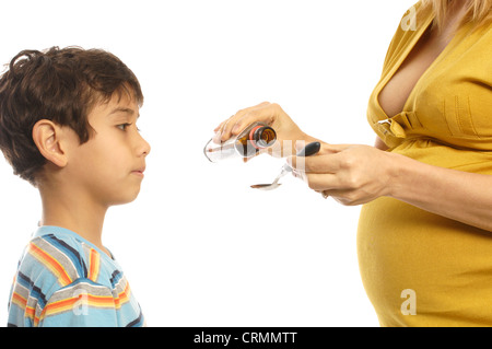 A mother pouring cough syrup for her young son to take Stock Photo