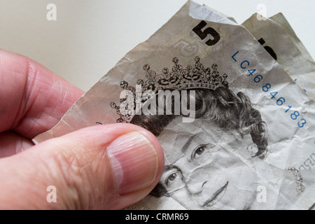 English currency paper money notes of £5 denomination folded and creased used held in hand Bank of England Stock Photo
