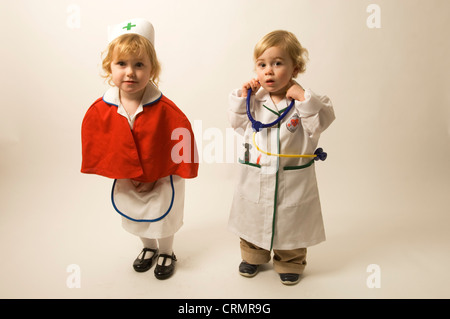 A young blonde girls dressed as a nurse standing beside a young blonde boy dressed as a doctor Stock Photo