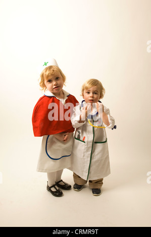 A young blonde girls dressed as a nurse standing beside a young blonde boy dressed as a doctor Stock Photo