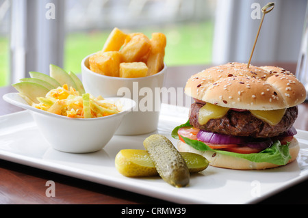 Gourmet cheese burger with chunky chips gherkins coleslaw and side salad Stock Photo