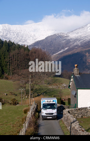 Tesco home delivery van parked outside remote cottage with snow-covered Mount Snowdon in background Gwynedd North Wales UK Stock Photo