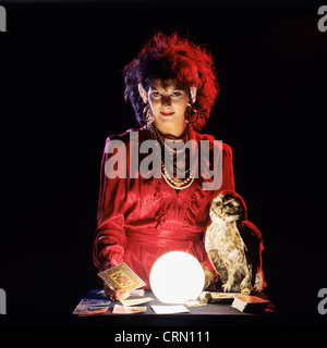 Gipsy fortune teller with an owl, tarot cards and lit crystal ball Stock Photo