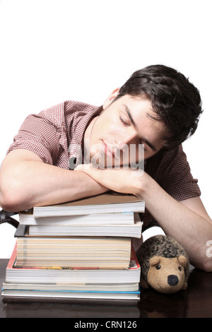 Eighteen year old male sleeping on school textbooks while sitting at a