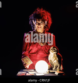 Gipsy fortune teller with an owl, tarot cards and lit crystal ball Stock Photo