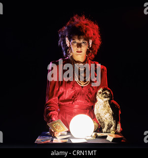 Gipsy fortune teller with an owl, tarot cards and lit crystal ball Stock Photo