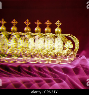 Multiple golden crown on garnet velvet Stock Photo