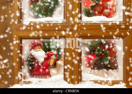 Falling snow against a festive Christmas frosty window scene Stock Photo